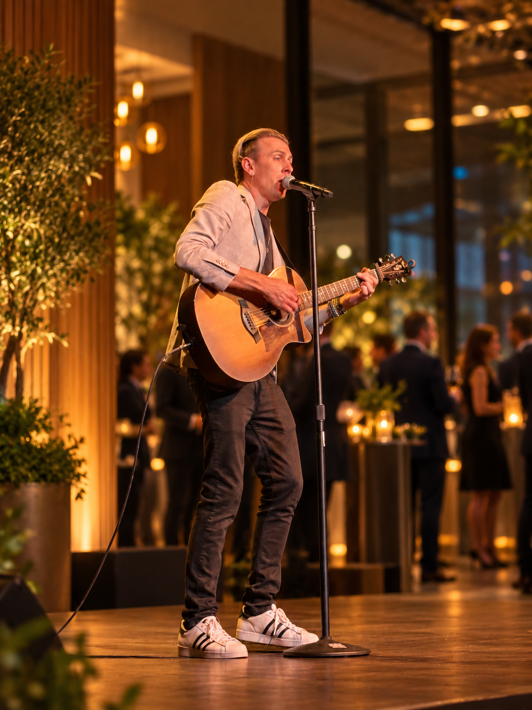 TREVAN singing and playing guitar in a grey jacket, with an edited event background